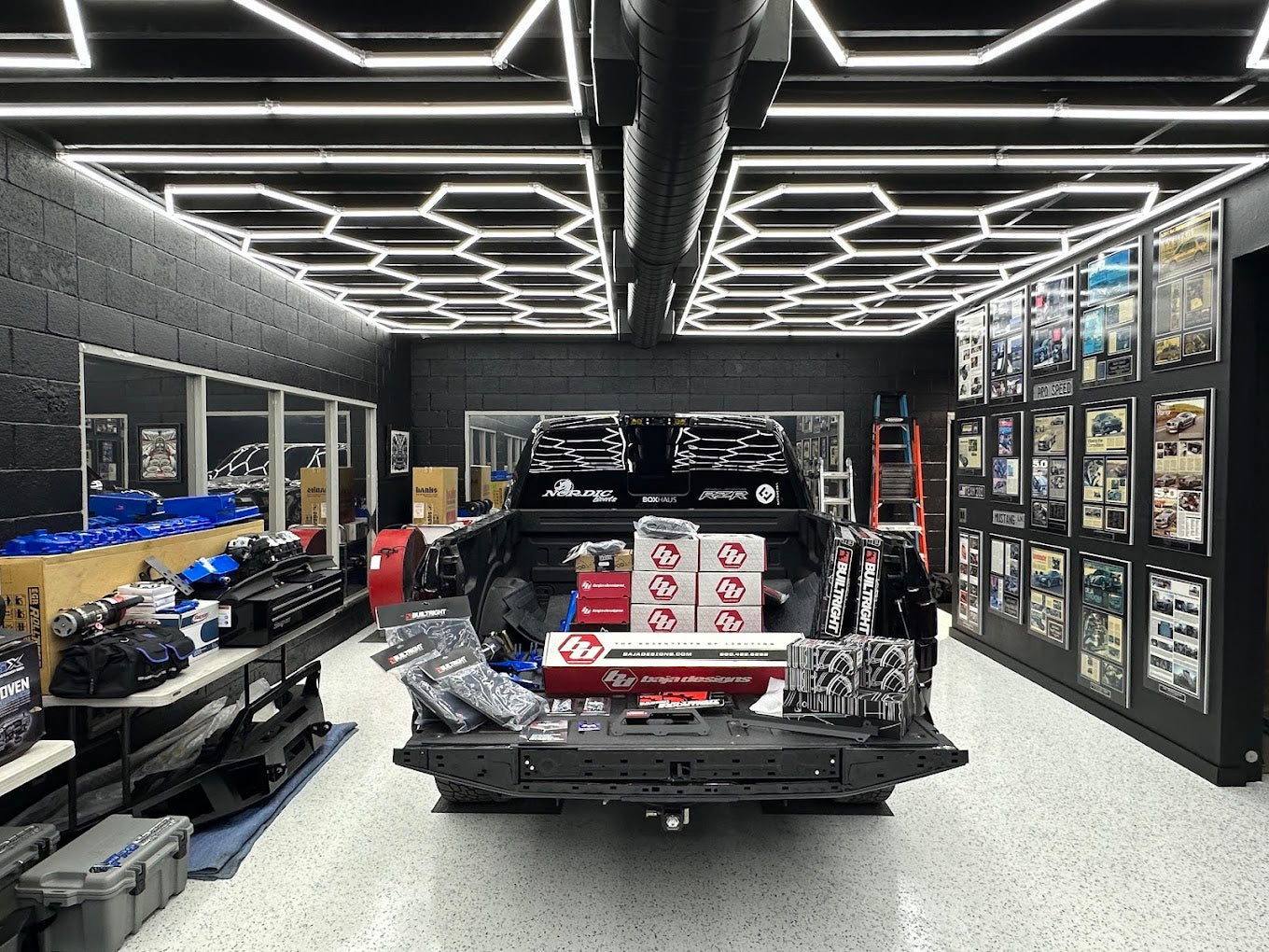 Hexagon LED ceiling lighting over a truck in a black-walled detail shop